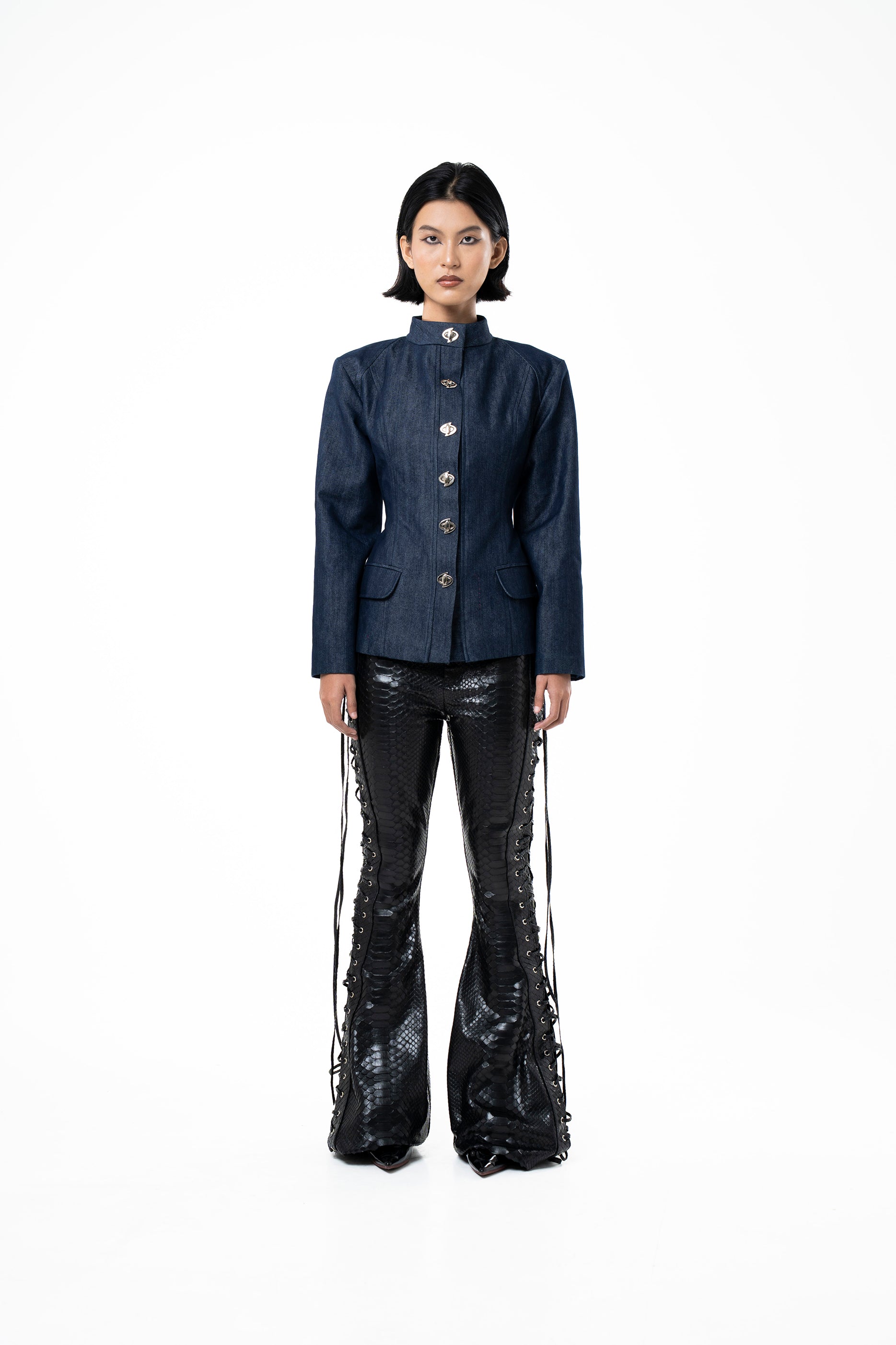 Person wearing a dark blue jacket and black flared pants on a white background